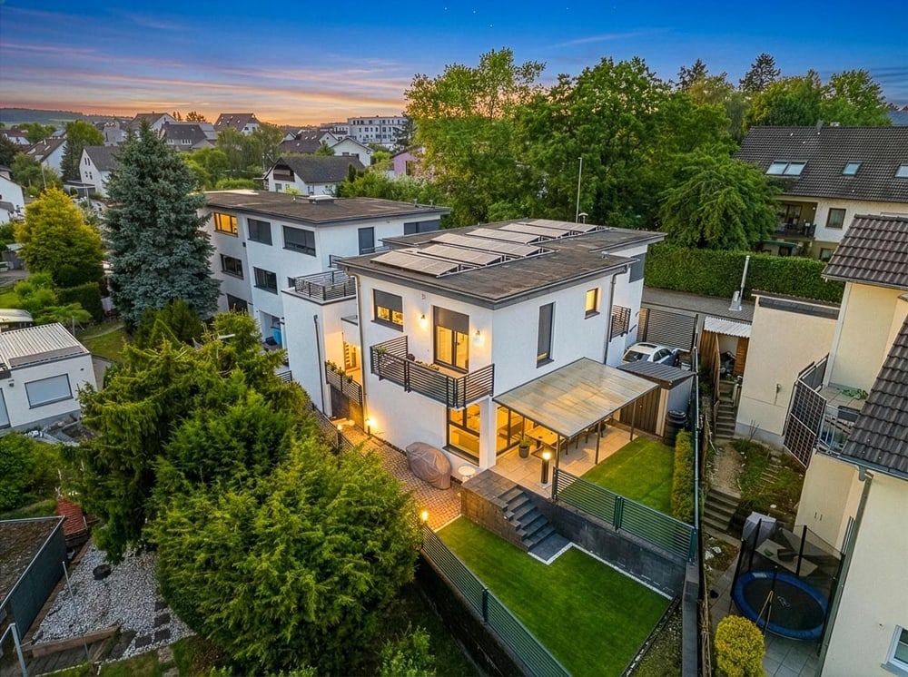 Modernes Haus mit beleuchteter Terrasse in der Dämmerung